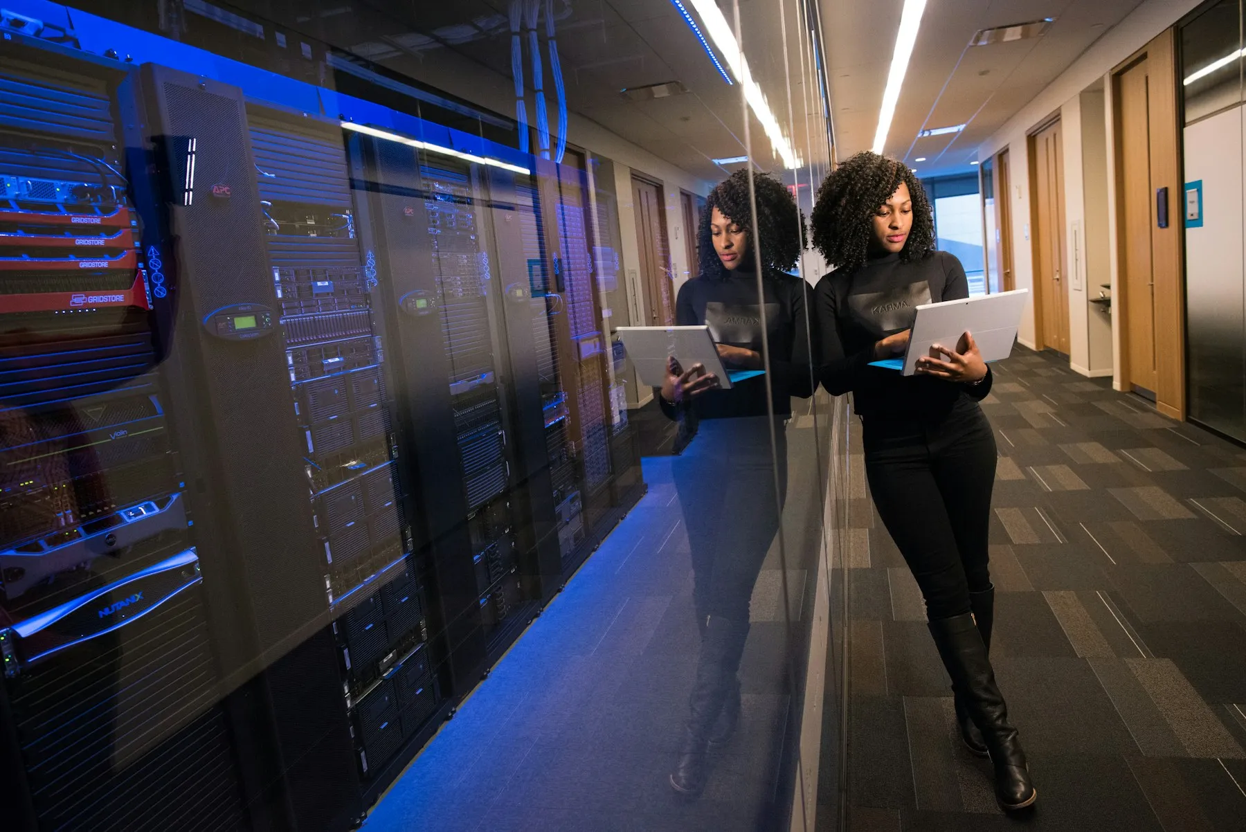 Engineer with a laptop walking through a data centre aisle